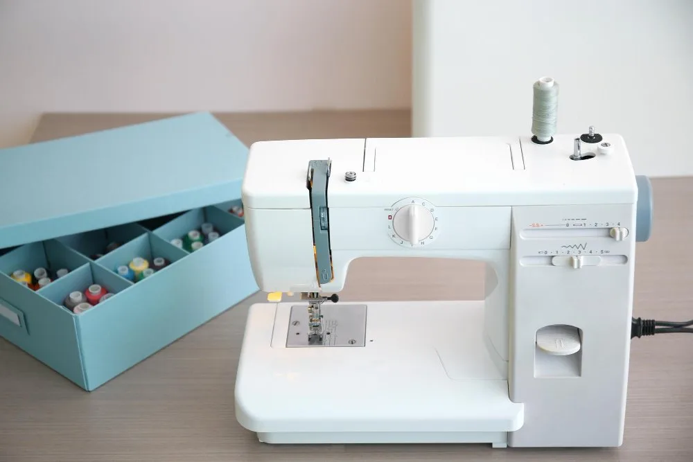 White sewing machine with thread storage box for beginner setup.