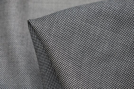 Detailed view of folded black and white Bird’s Eye fabric showing its fine diamond pattern.