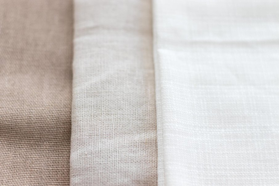 Close-up view of three types of cambric cotton fabric in beige and white tones.