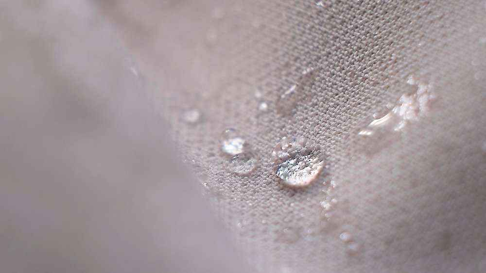 Waterproof coated cotton fabric with visible water droplets on the surface, showing water-repellent and durable texture