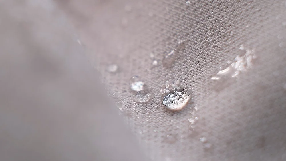 Waterproof coated cotton fabric with visible water droplets on the surface, showing water-repellent and durable texture
