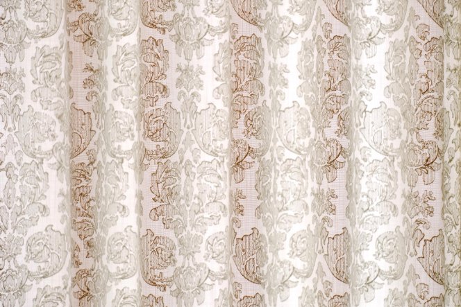 Light-colored damask linen curtain with floral woven pattern.