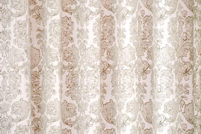 Light-colored damask linen curtain with floral woven pattern.