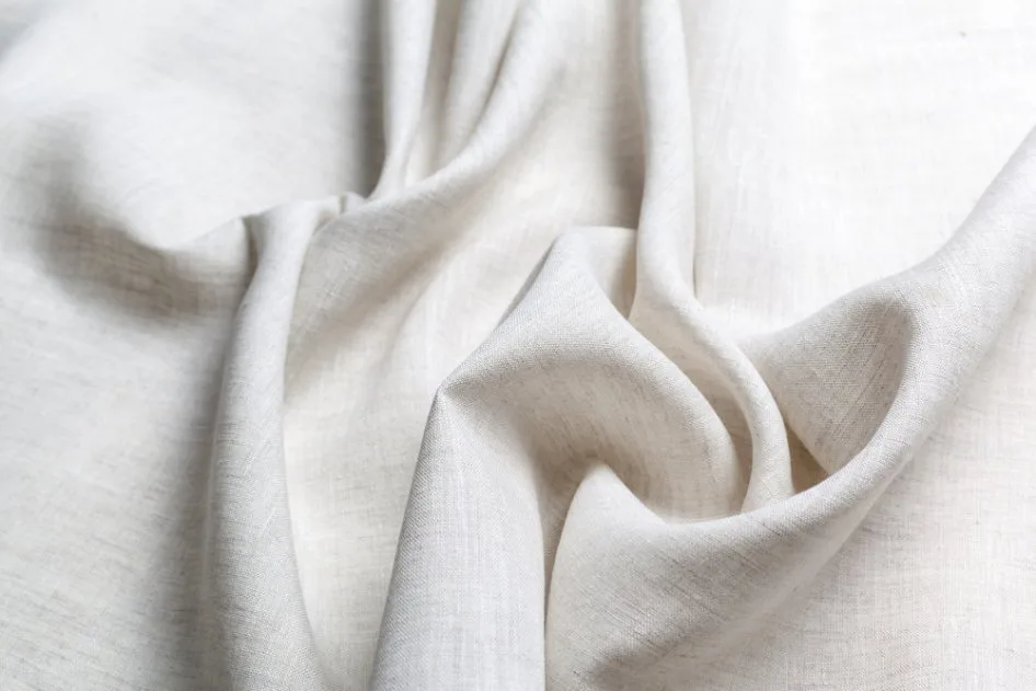 Close-up of smooth white Holland linen fabric with soft folds and fine texture.