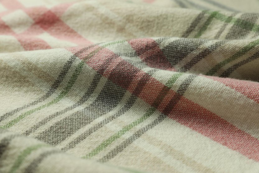 Close-up of colorful Huckaback linen fabric with red, green, and beige stripes highlighting its woven texture.