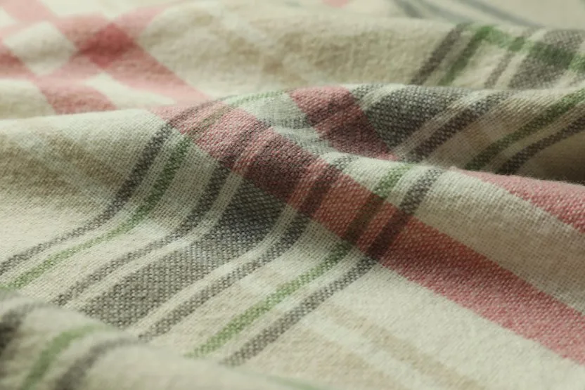 Close-up of colorful Huckaback linen fabric with red, green, and beige stripes highlighting its woven texture.