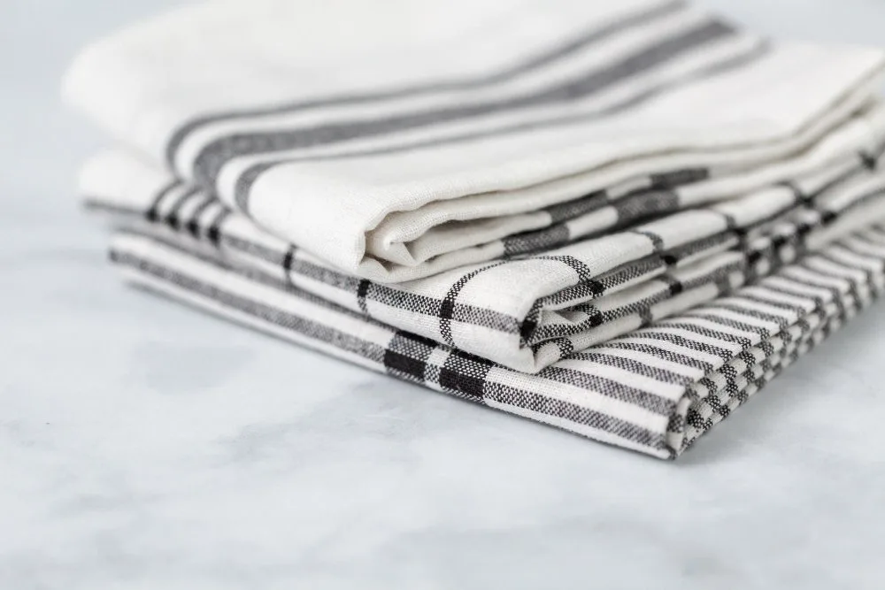 Folded black-and-white checked and striped linen towels on marble