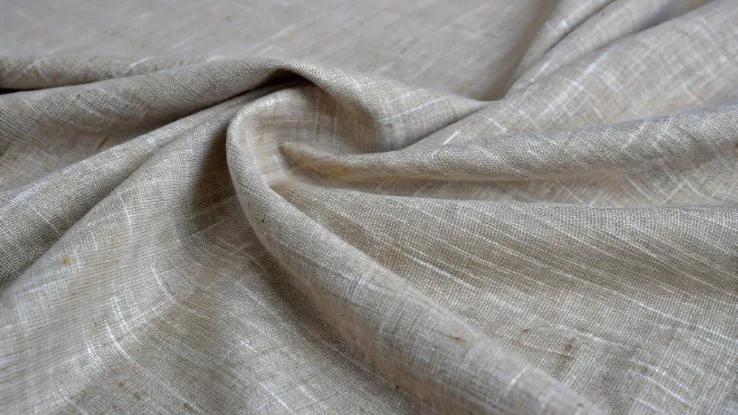Close-up of beige mélange weave linen fabric showing its natural texture and subtle luster.