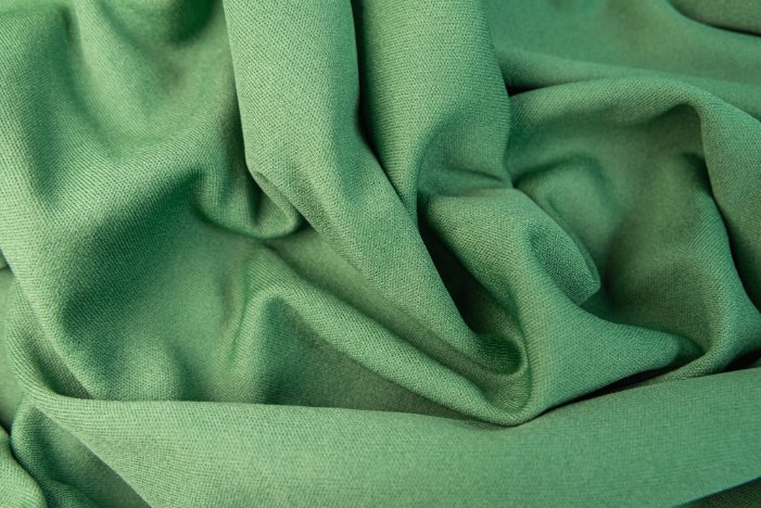 Close-up of green bio-based polyester fabric with a soft, smooth surface texture.