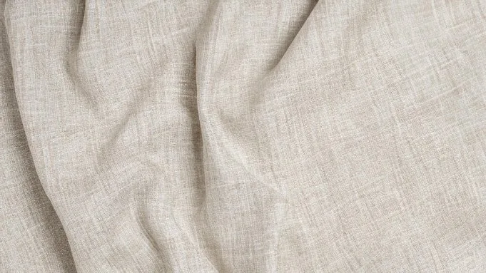 Close-up of beige linen fabric with a natural woven texture and soft drape.