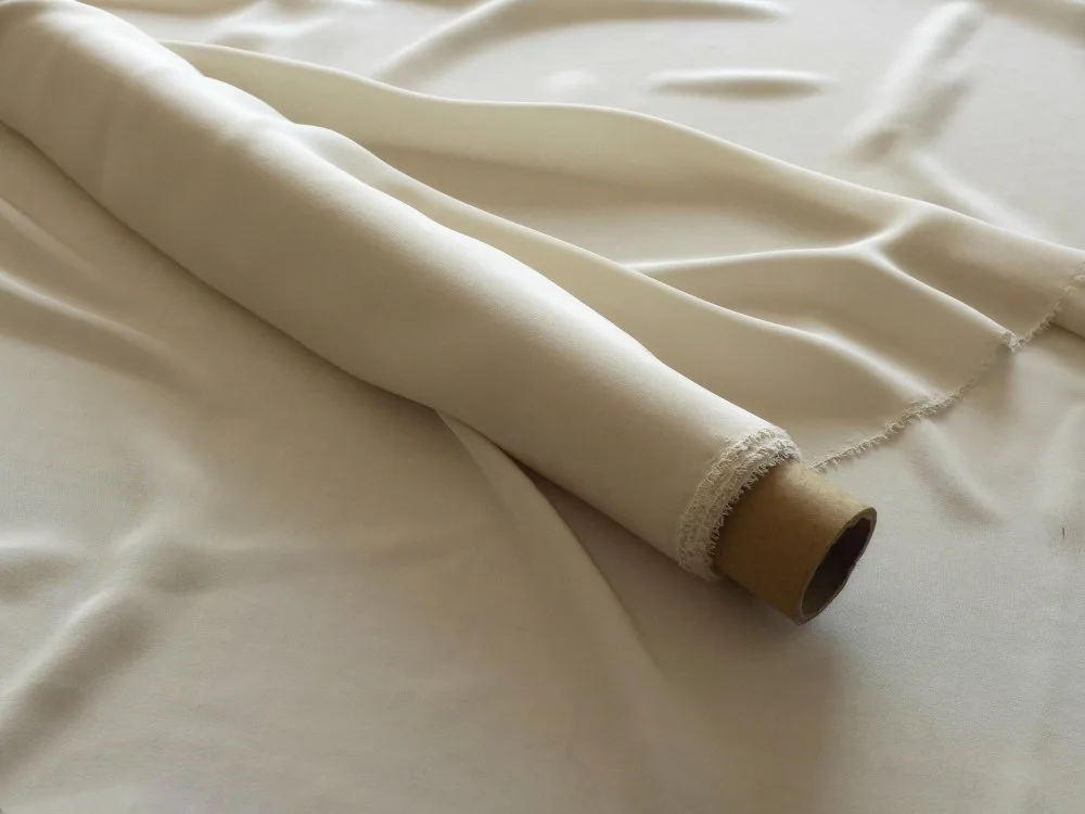 Roll of off-white sheeting linen fabric showing soft drape and fine weave.