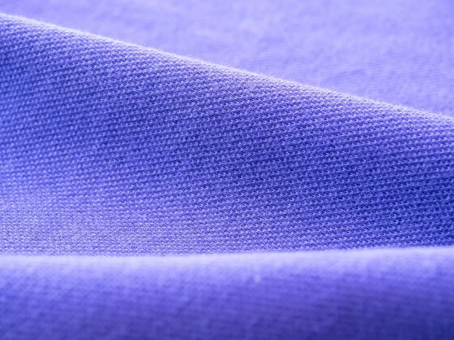 Close-up view of soft purple spun polyester fabric showing fine weave texture.
