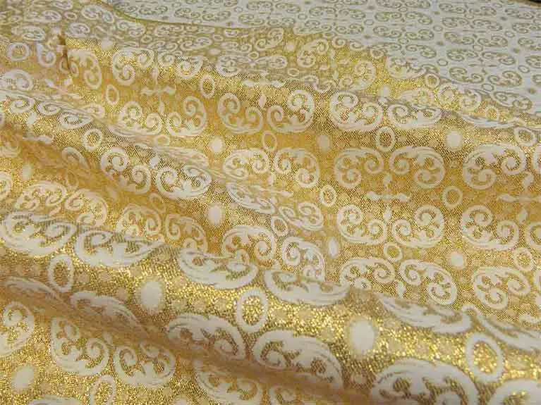 Ivory and gold brocade fabric draped in folds with ornate decorative patterns