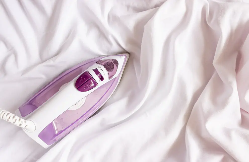 Purple and white steam iron on white satin fabric for gentle care