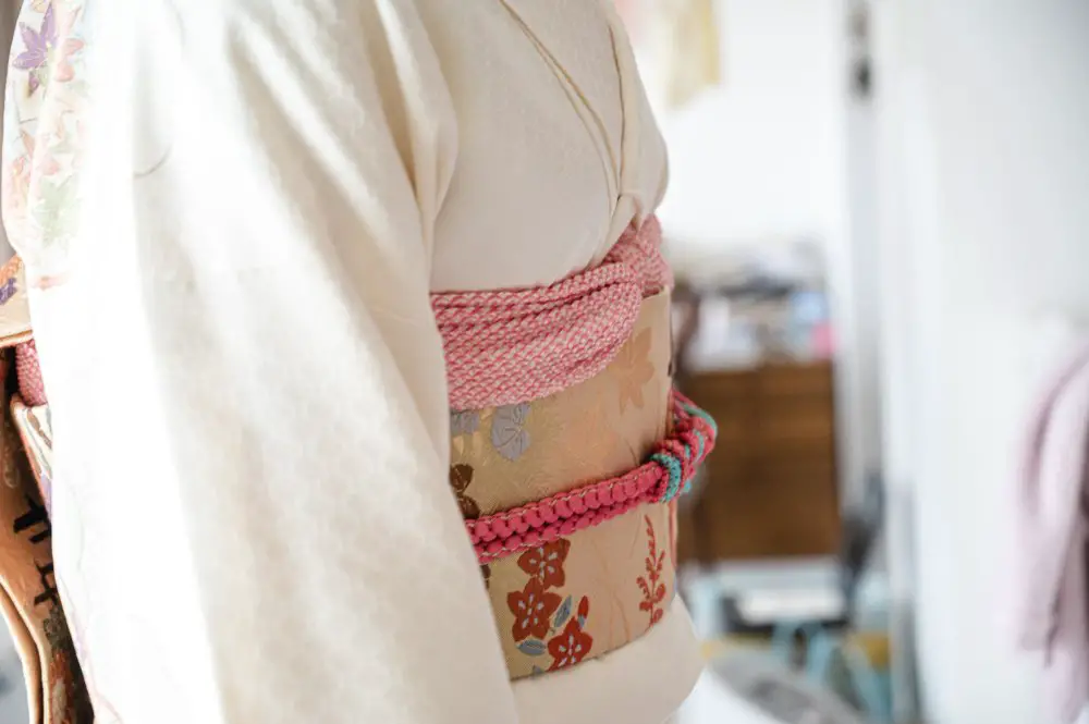 Close up of a traditional kimono showing textured silk fabric and decorative obi belt