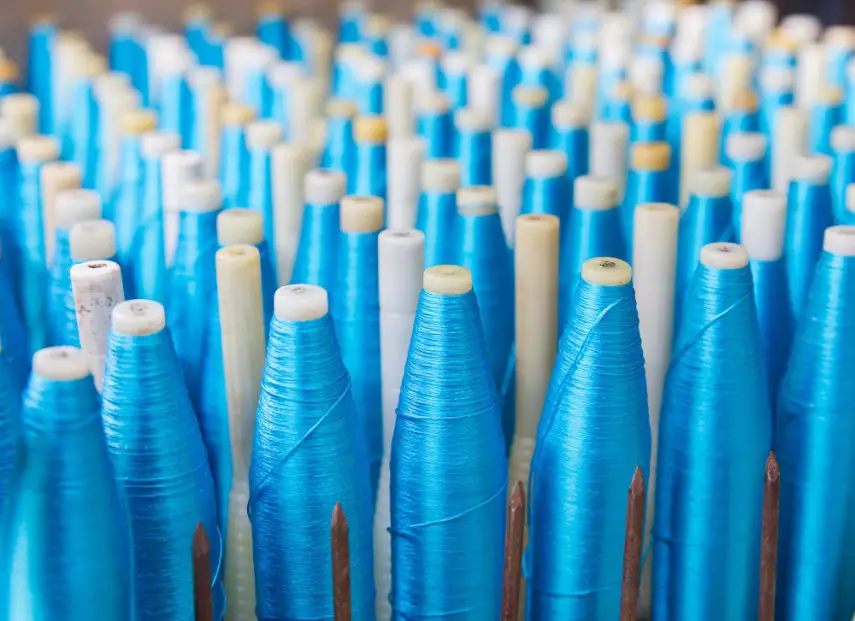 Blue satin thread spools arranged in rows at a textile production facility