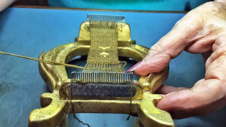 Hands spinning sea silk fibers using a traditional tool to prepare fine golden threads