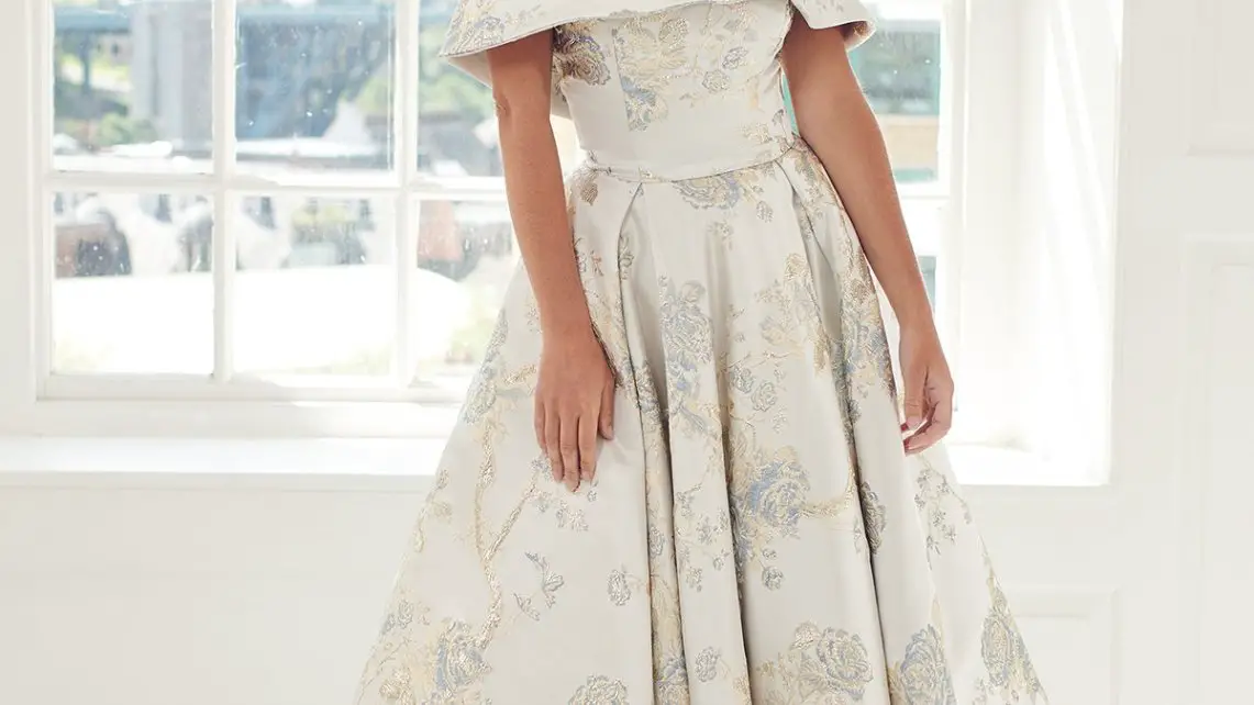 Elegant dress made from cream and gold brocade fabric worn by a model in a bright room