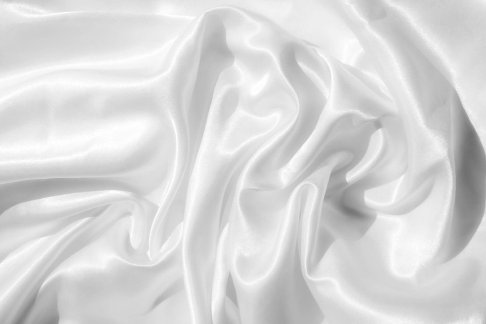 White polyester slipper satin fabric draped in soft folds with a glossy, reflective surface