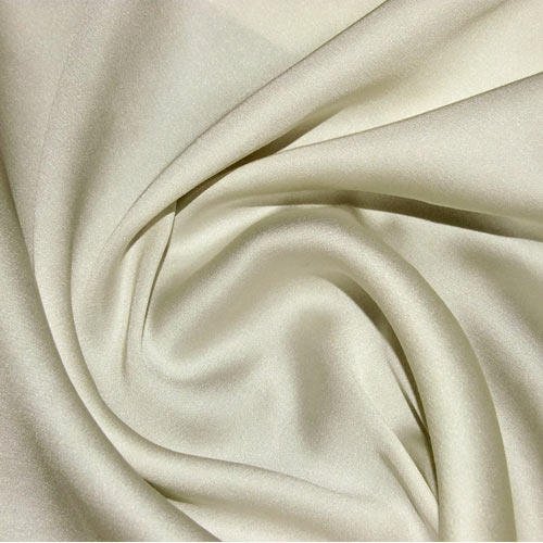 Close up of cream raw silk fabric draped into soft folds showing natural texture