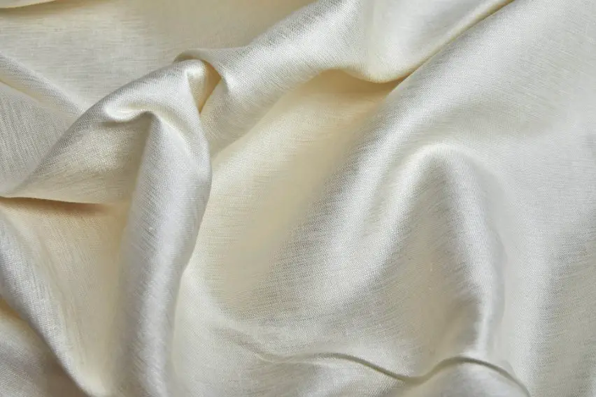 Close up of ivory raw silk fabric showing natural slubs and soft sheen