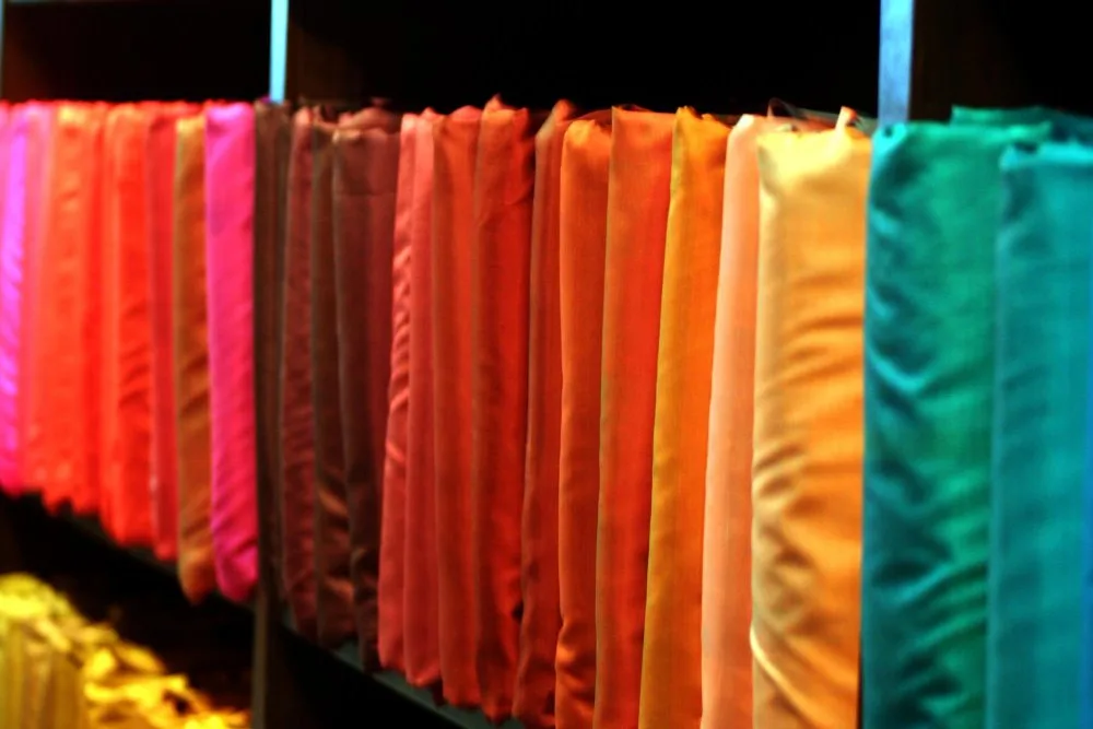 Colorful rolls of Shantung fabric arranged in a row showcasing a wide range of vibrant shades