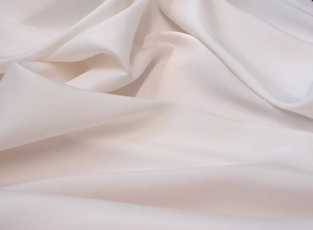 Close up of soft ivory Shantung fabric showing its smooth texture and gentle folds