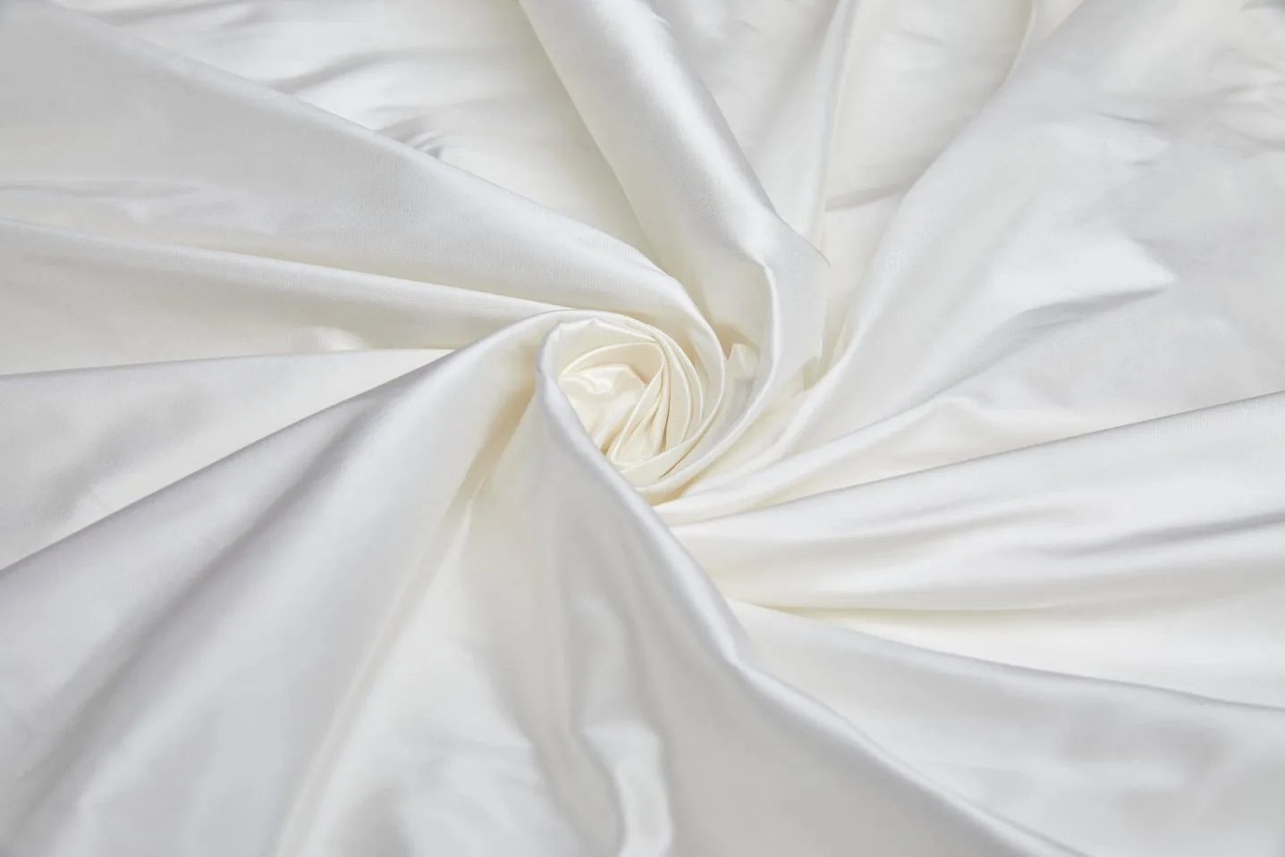 Luxurious white silk taffeta fabric arranged in elegant folds with a natural sheen