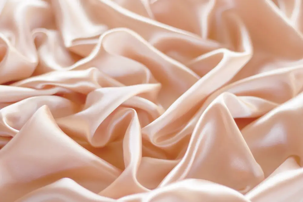 Close up of peach colored silk fabric with glossy satin finish