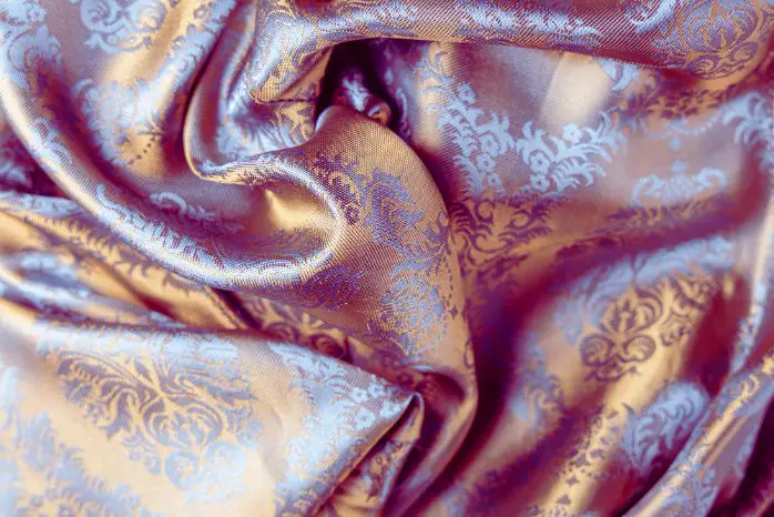 Close up of Banarasi silk fabric with gold and blue brocade patterns symbolizing the heritage of Varanasi weaving