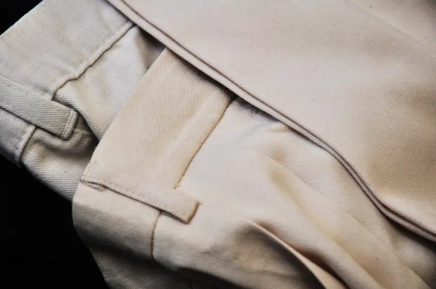 Close up of folded beige trousers showing raw silk blend fabric texture and structure