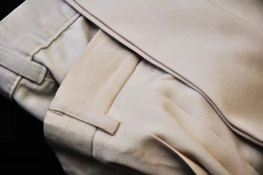 Close up of folded beige trousers showing raw silk blend fabric texture and structure