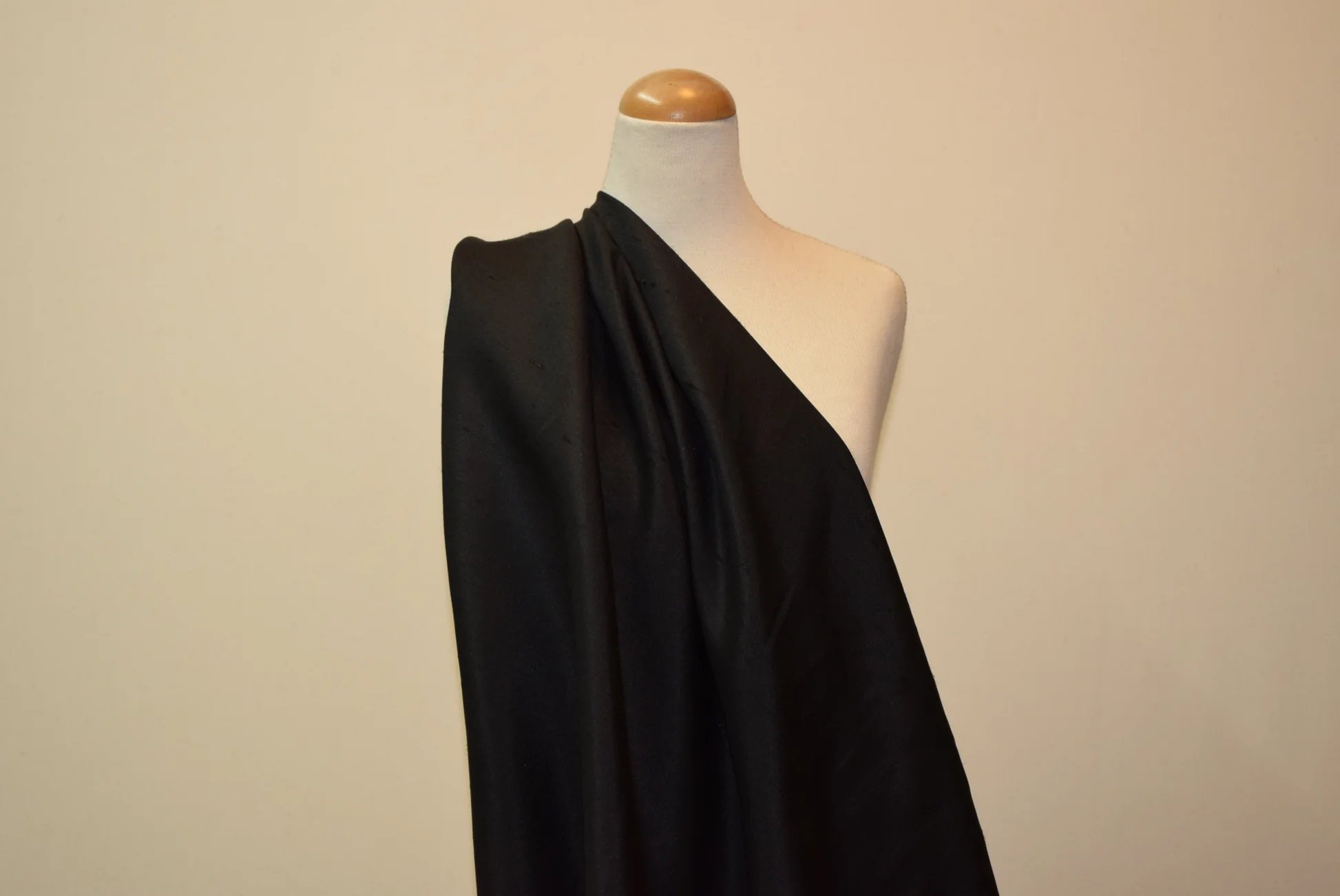 Black Shantung fabric draped over a dress form to demonstrate drape and texture