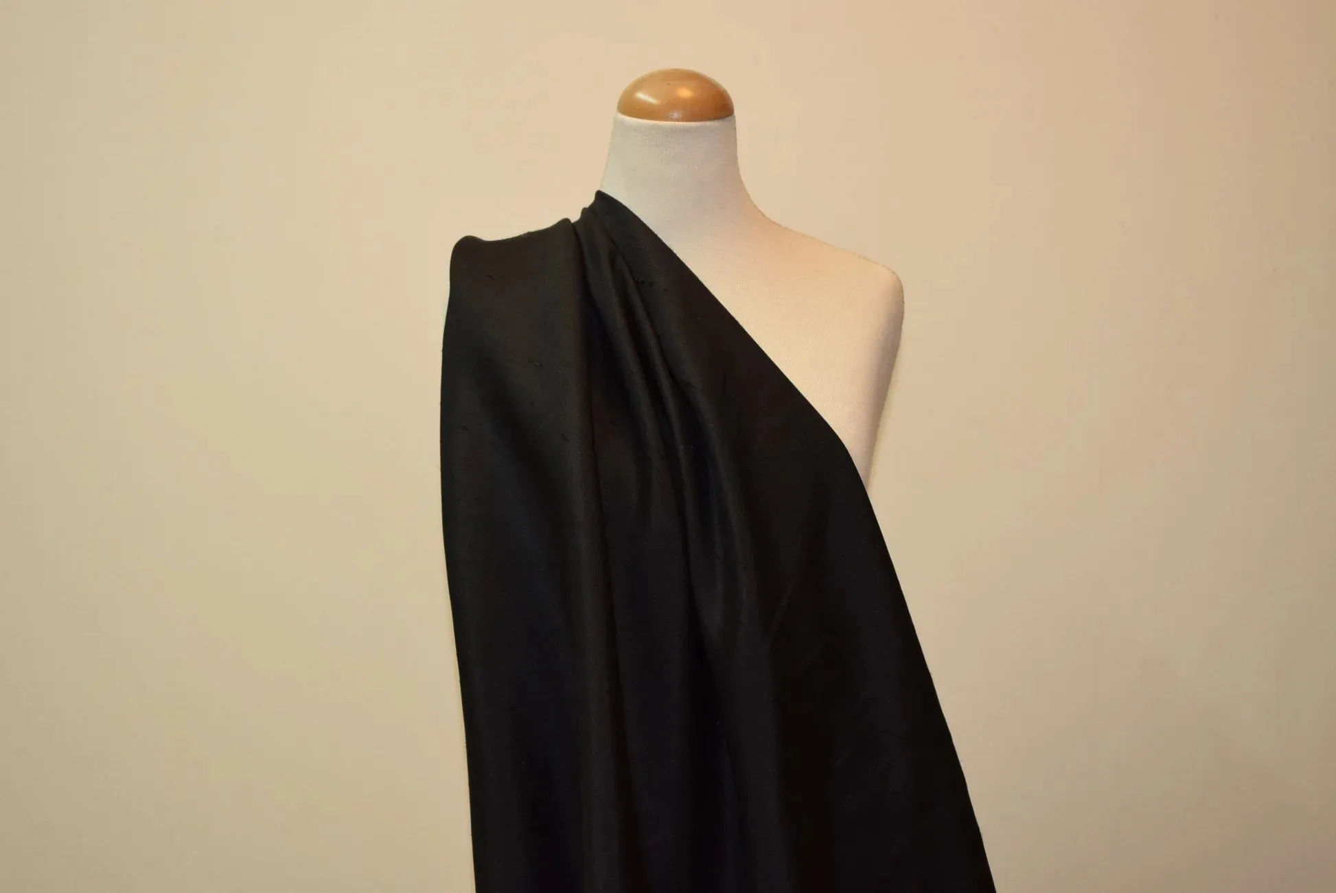 Black Shantung fabric draped over a dress form to demonstrate drape and texture