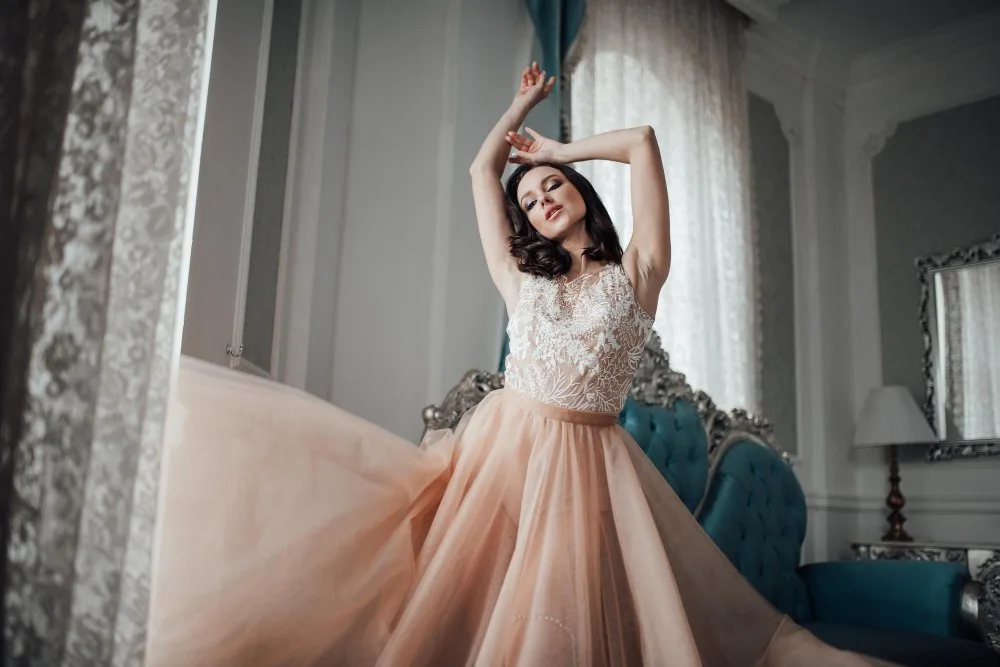 Woman in a peach-colored organza gown posing elegantly in a luxurious room