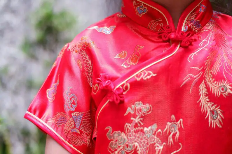 Red Canton silk cheongsam with gold embroidered dragon patterns worn by a woman