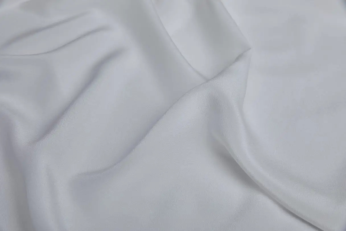 Close-up of white Crepe de Chine fabric showing smooth matte finish and gentle drape