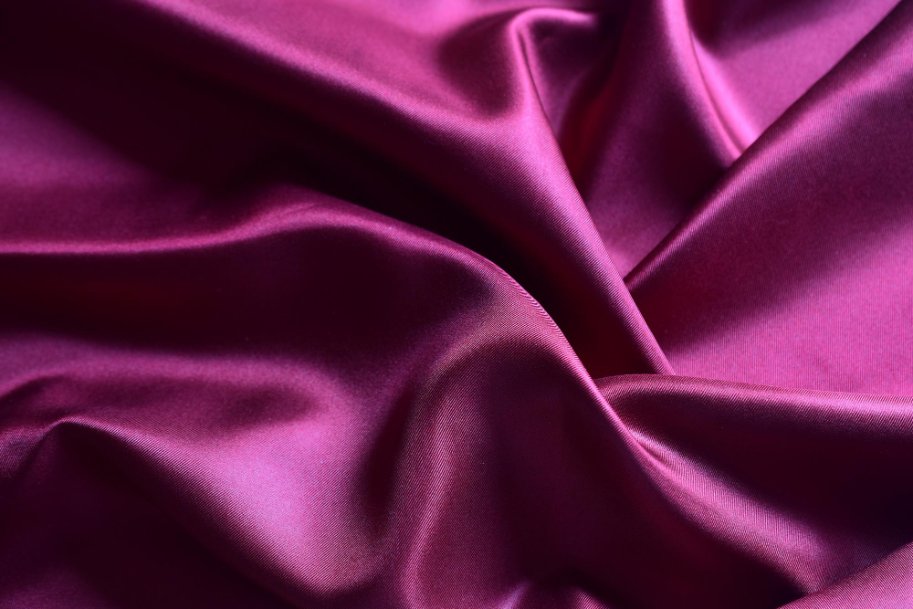 Close up of smooth deep pink mulberry silk fabric with elegant shine