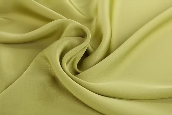 Light green acetate chiffon fabric arranged in soft twists showing its airy and semi translucent texture