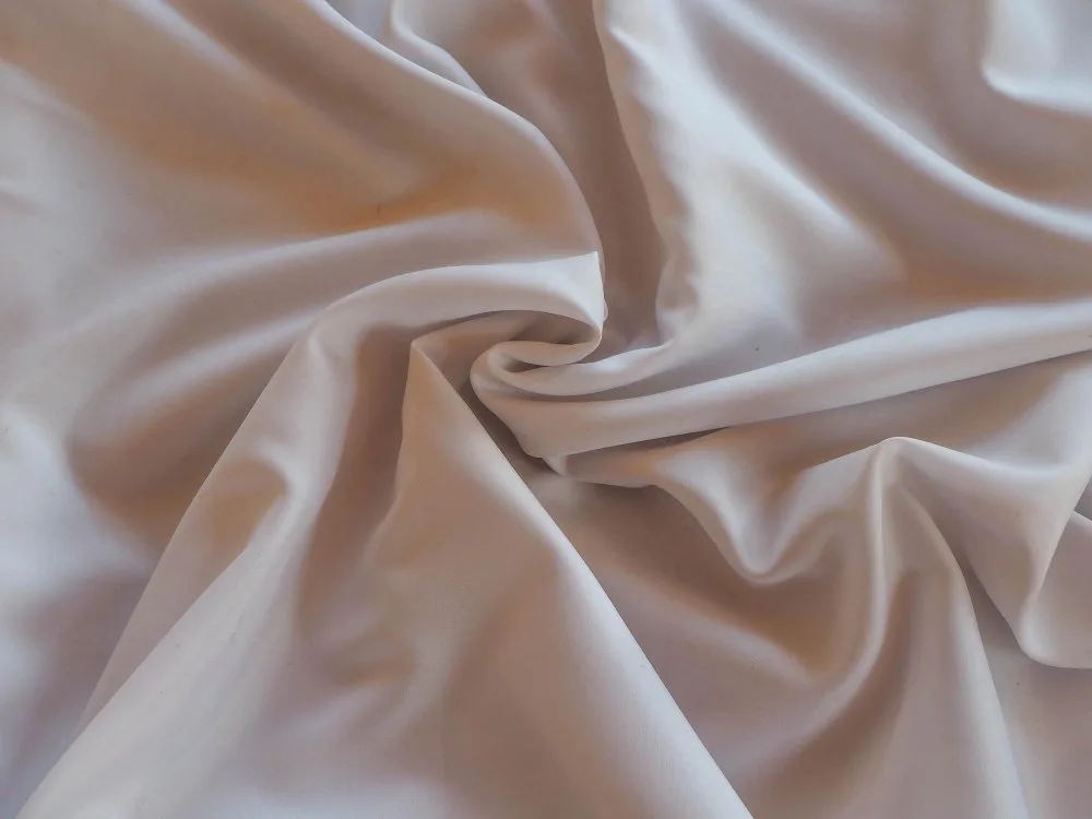 White acetate satin fabric draped with a central twist to highlight its glossy sheen and soft hand feel