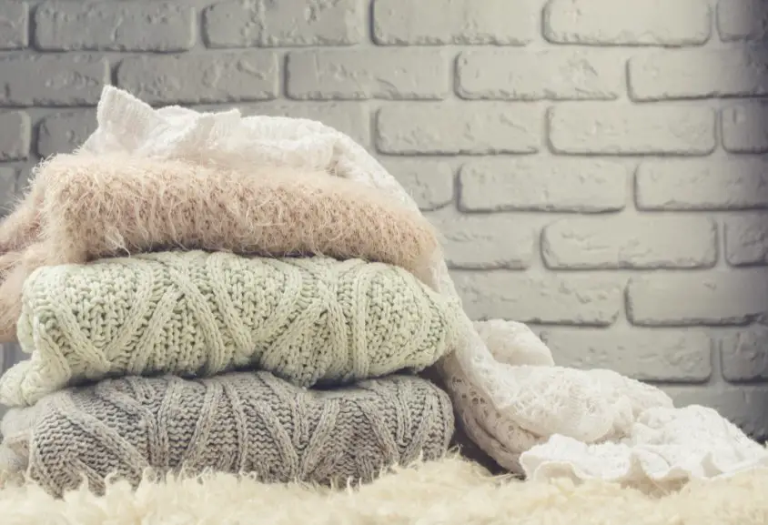 Stack of folded mohair knit sweaters in soft neutral colors