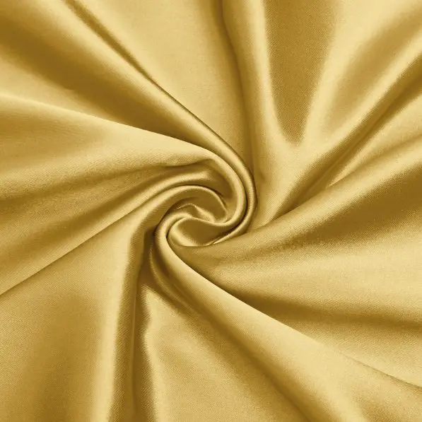 Gold charmeuse satin fabric gathered into a swirl to showcase its glossy texture and fluid drape