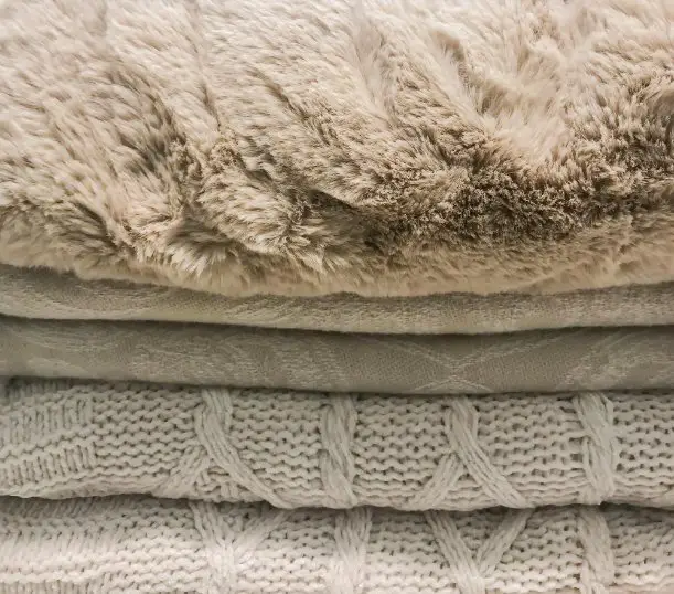 Stacked alpaca garments illustrating proper care and storage