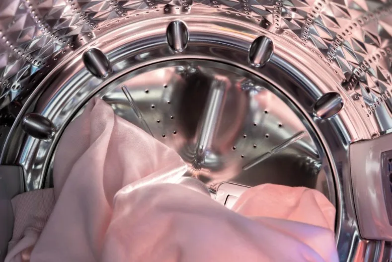 Lucent satin garments inside a washing machine drum during a gentle cycle