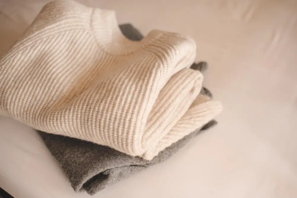 Folded cashmere sweaters stacked neatly to demonstrate proper storage and care