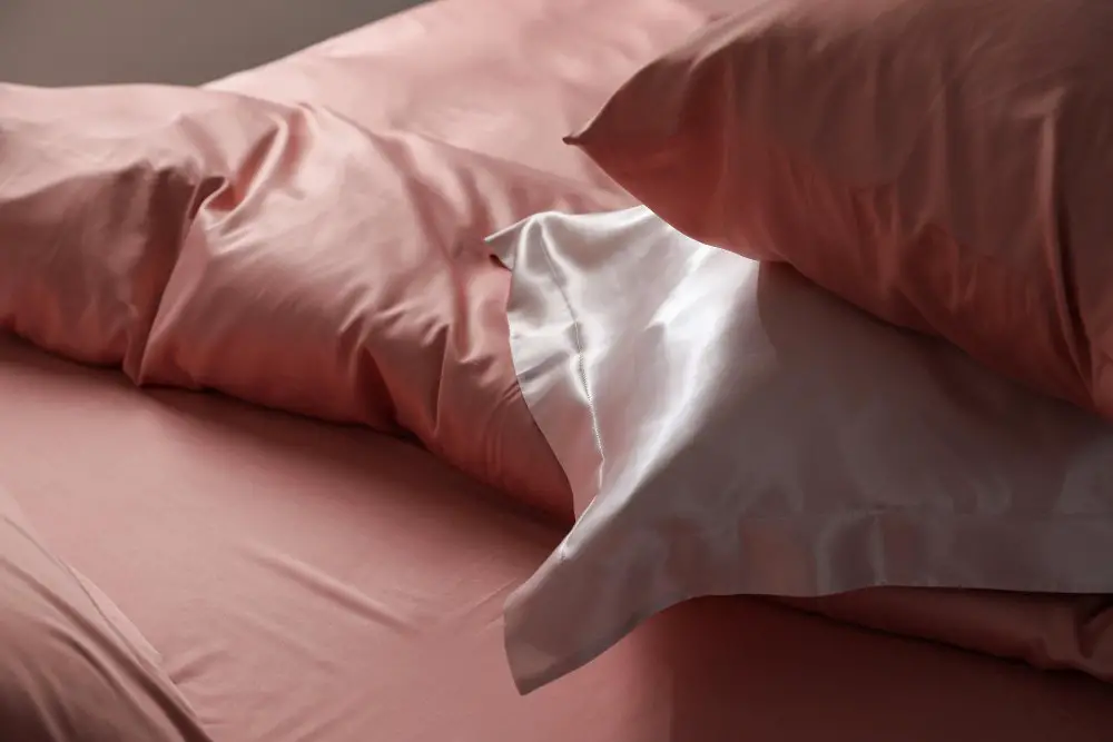 Pink stretch satin bedding with pillowcases showing soft sheen and smooth texture