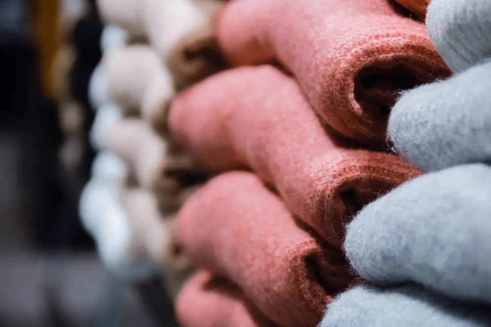 Stacked merino wool sweaters in different colors displayed in a retail setting