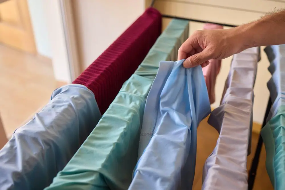 Person hanging polyester satin garments on a drying rack to air dry