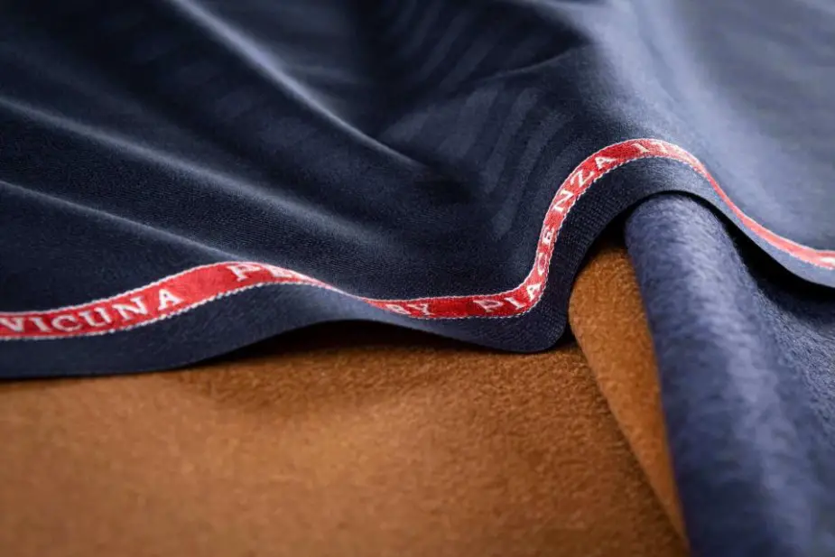 Luxury vicuña fabric with branded selvedge indicating premium quality and authenticity