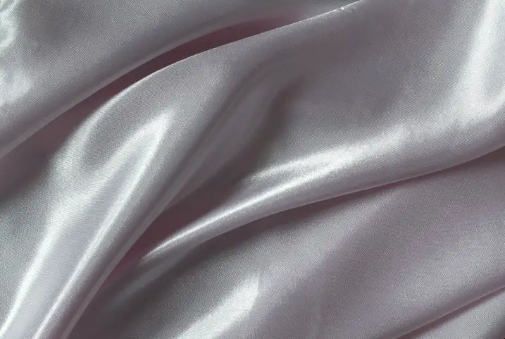 Close up of pale lilac lucent satin fabric with soft ripples and a subtle glossy finish